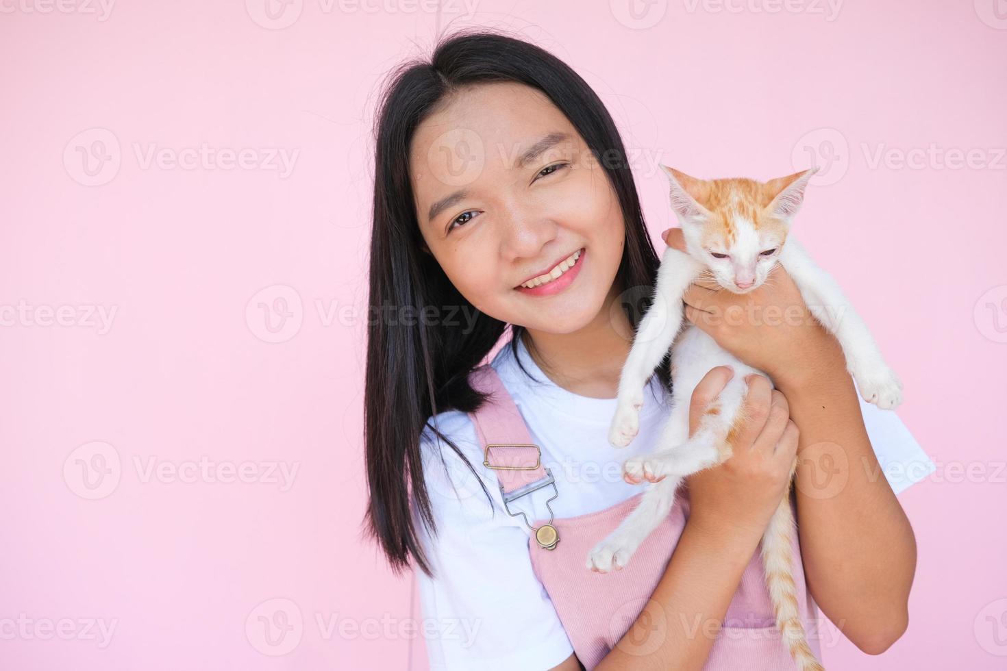 Smile young girl with cat on pink background. photo