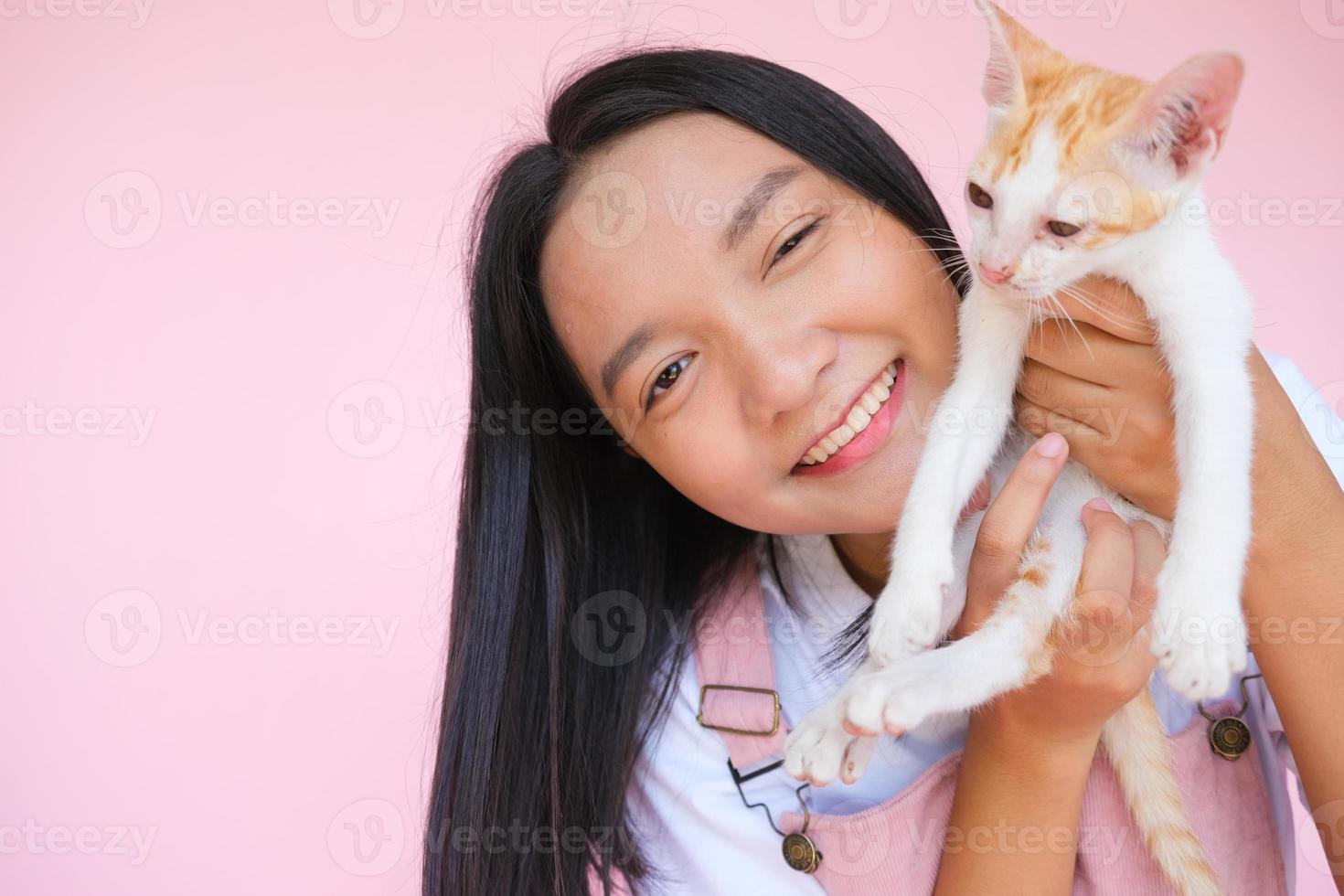 Smile young girl with cat on pink background. photo