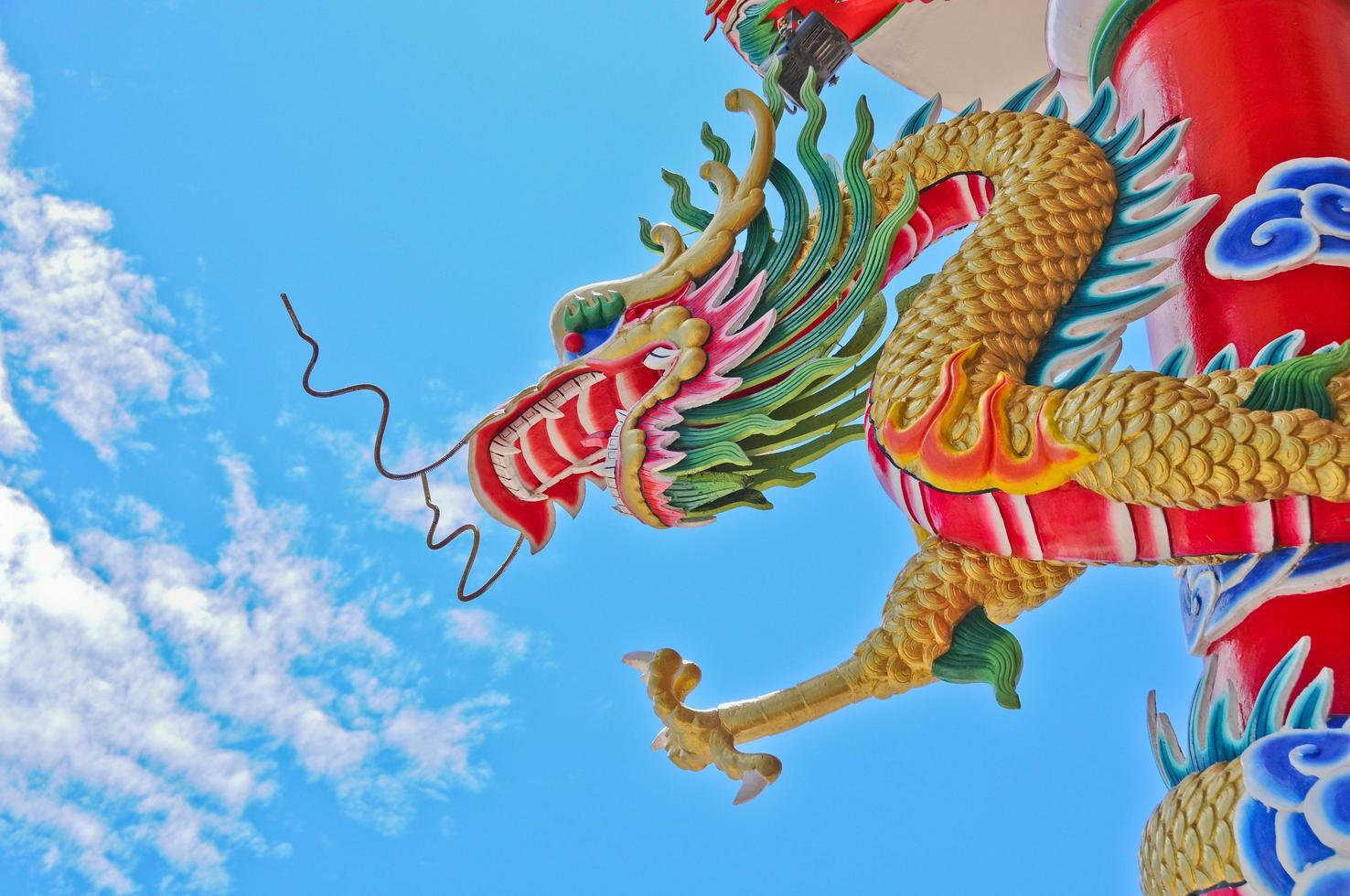 Golden flying majestic Asian Chinese dragon statue with blue sky in sunny day photo