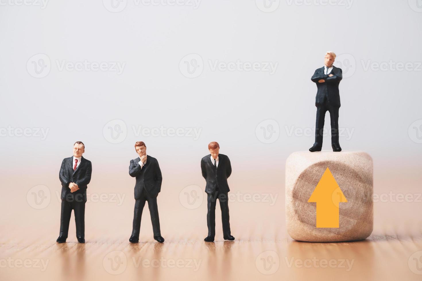 Businessman standing on wooden cube which higher level from three businessmen standing on floor for promotion from staff to management concept. photo