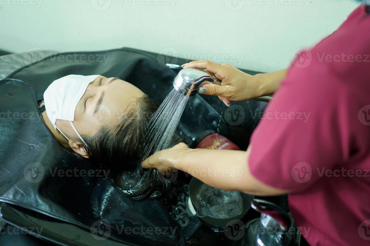 Professional hair stylist making a hair coloring and treatment in beauty and salon shop. Woman changing a hair color in professional salon shop. photo