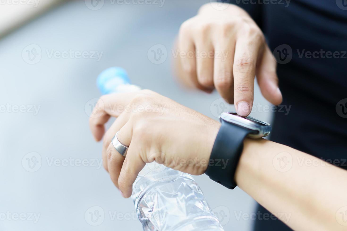 Active Asian young sportsman using a smartwatch or smart fitness band to track his outdoor workout and activities, man reviewing an exercise and health information after finished outdoor workout. photo