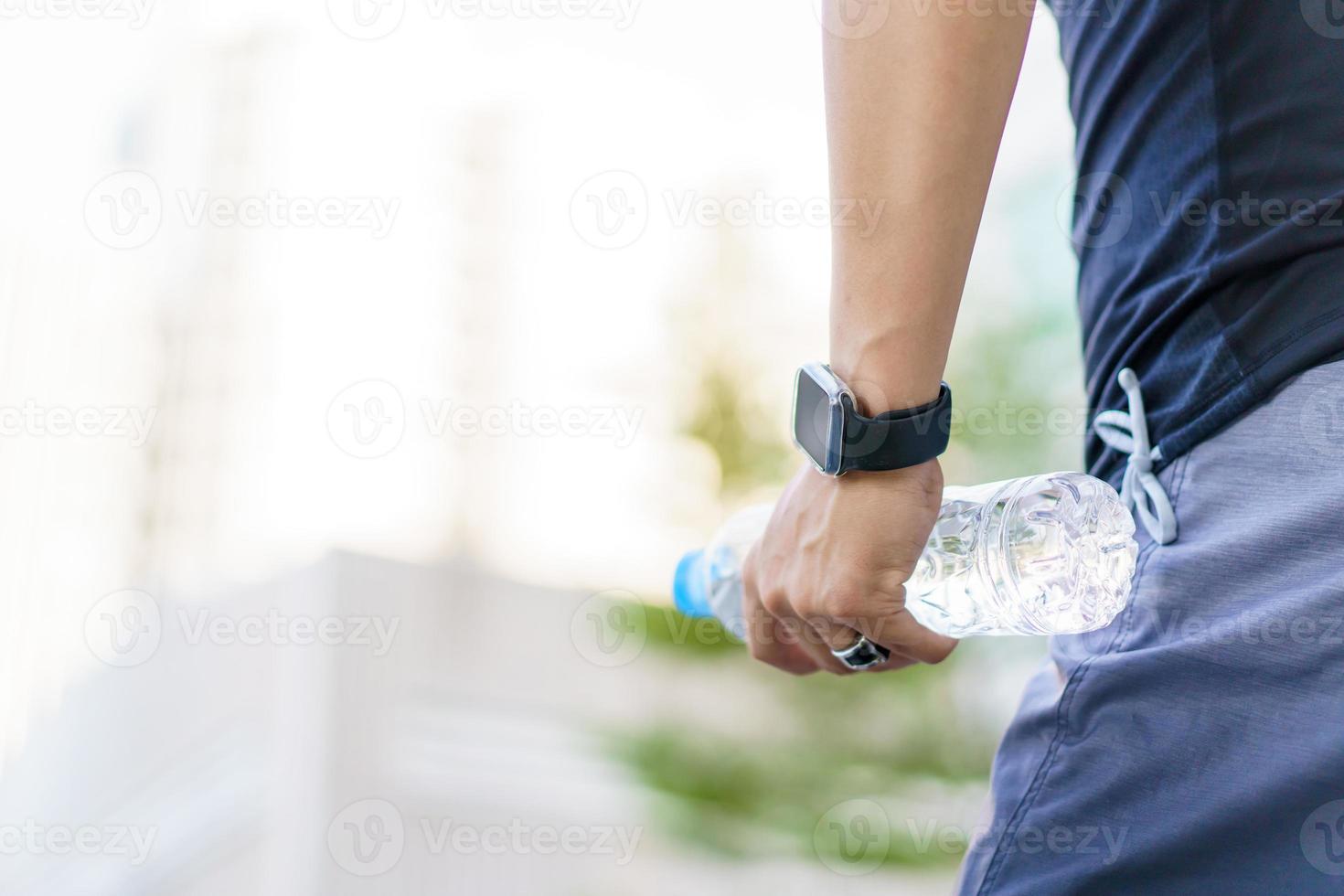 Active Asian sportsman relaxing and drinking a water in bottle after outdoor running or workout. Asian man drink a water during the break from exercise. A healthy man trying hard for cardio workout. photo
