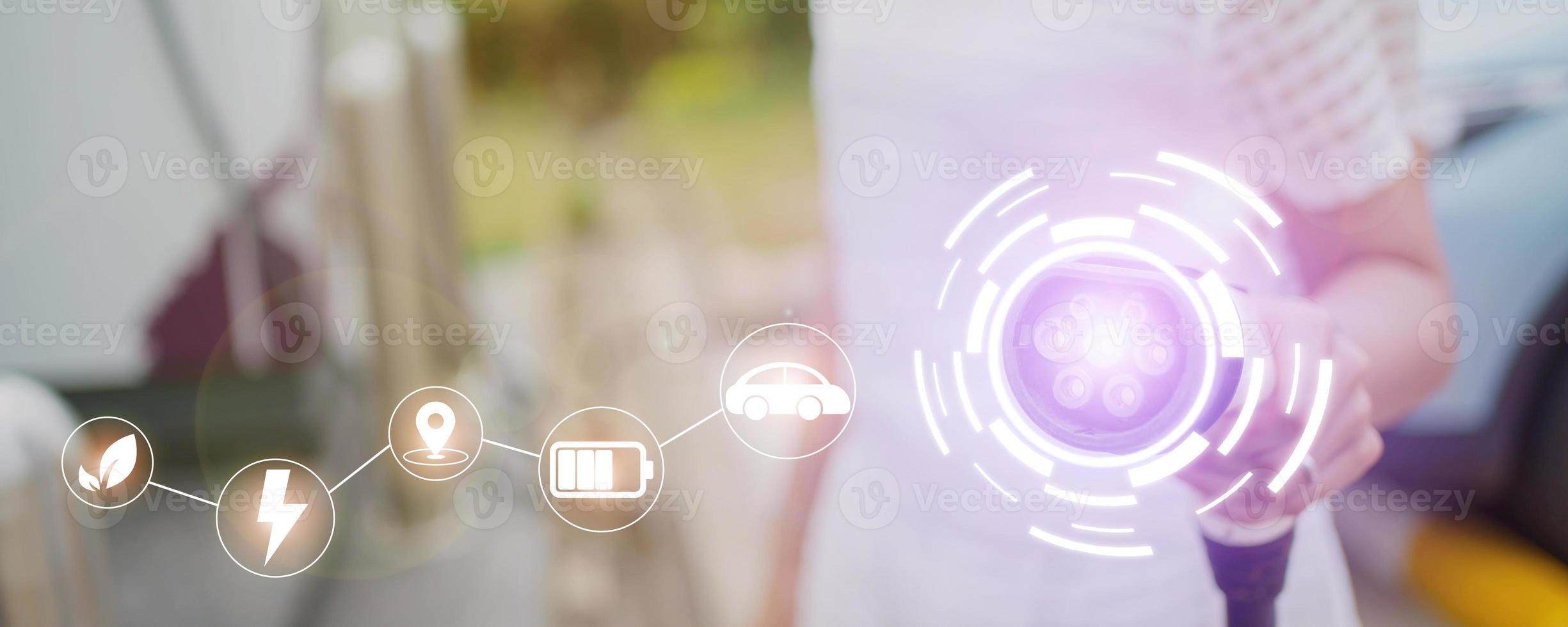 Happy Asian woman holding a DC - CCS type 2 EV charging connector at EV charging station, woman preparing an EV - electric vehicle charging connector for recharge a vehicle. photo