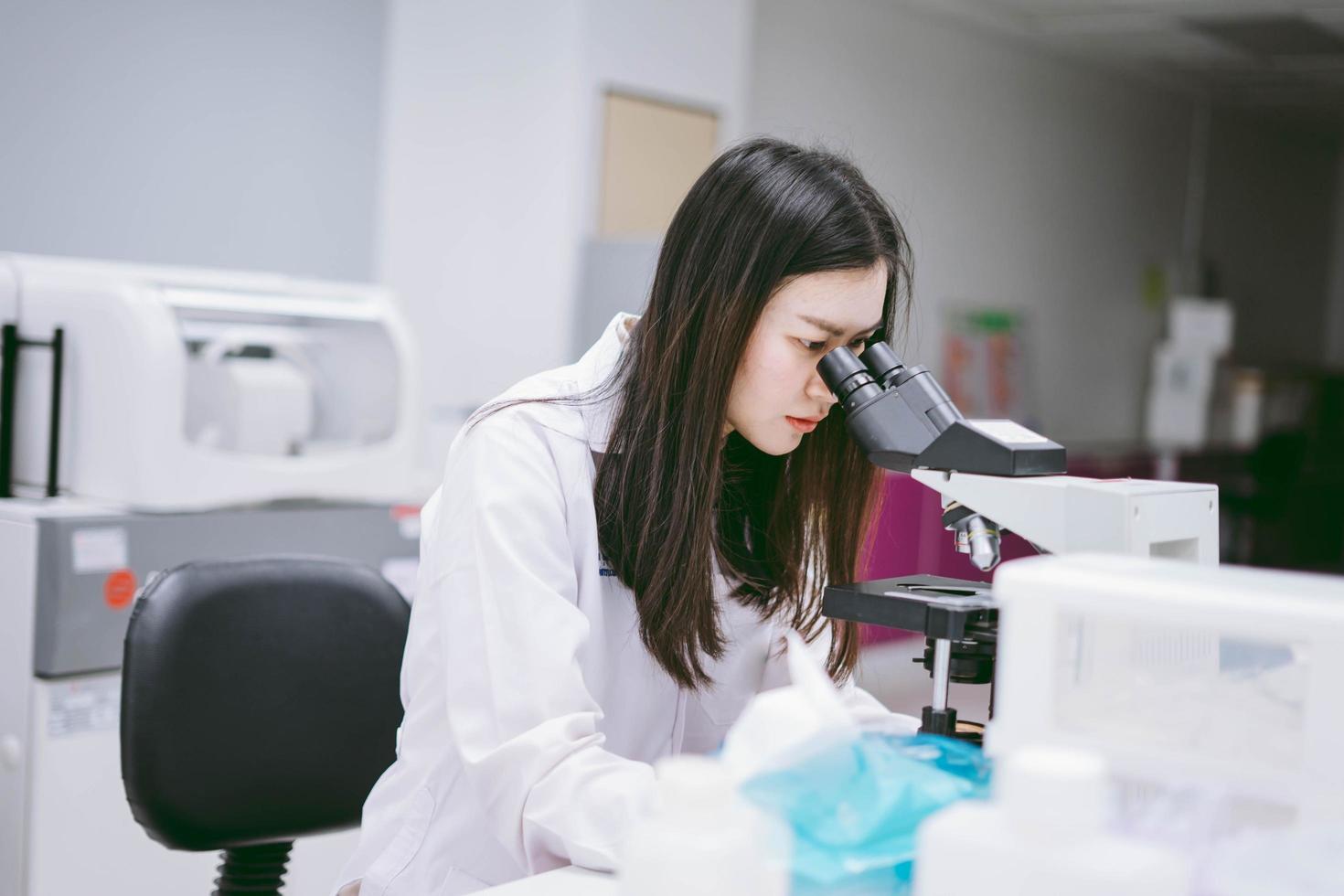 joven científica mirando el microscopio en el laboratorio médico foto