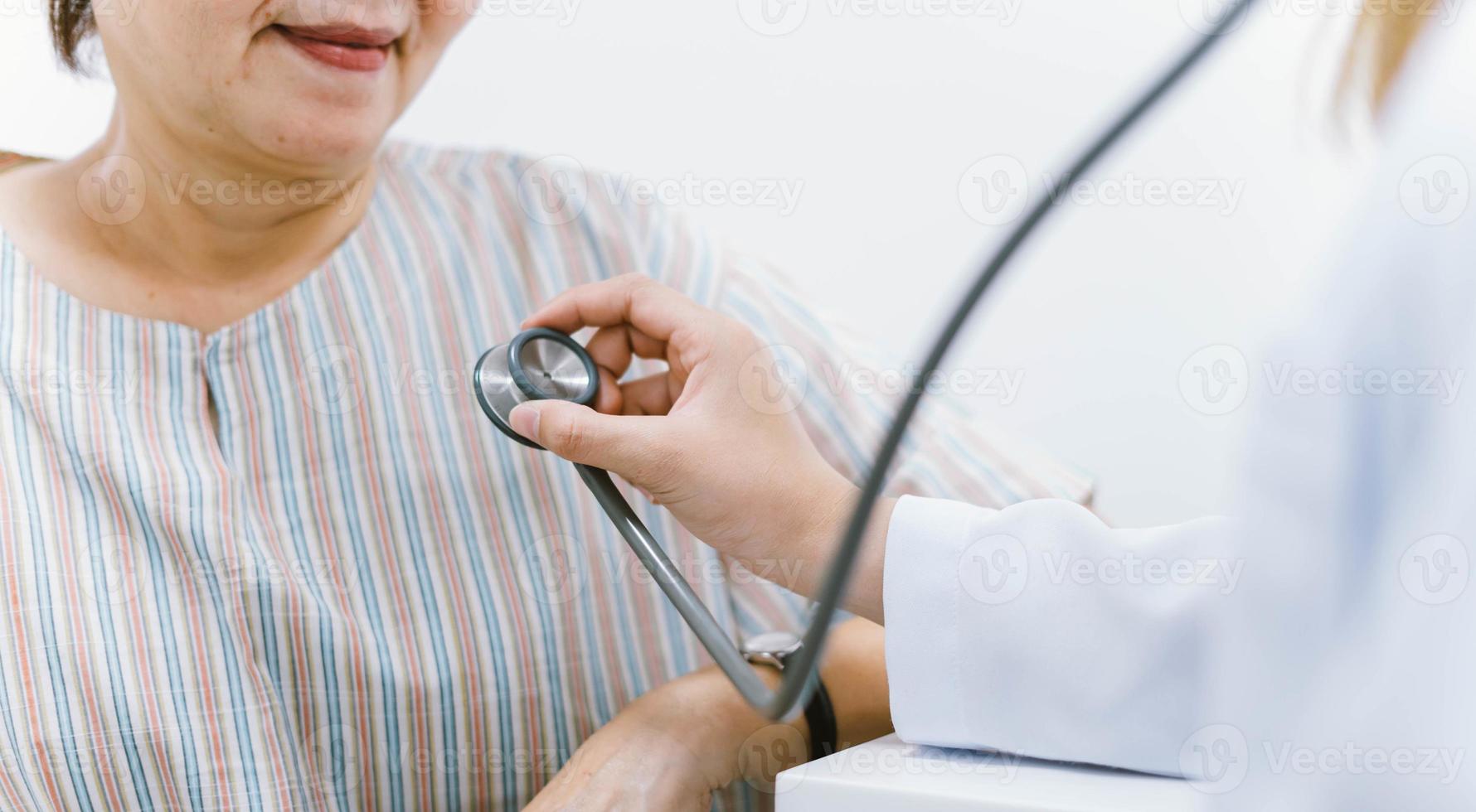 Young doctor using stethoscope to exam senior patient heart photo