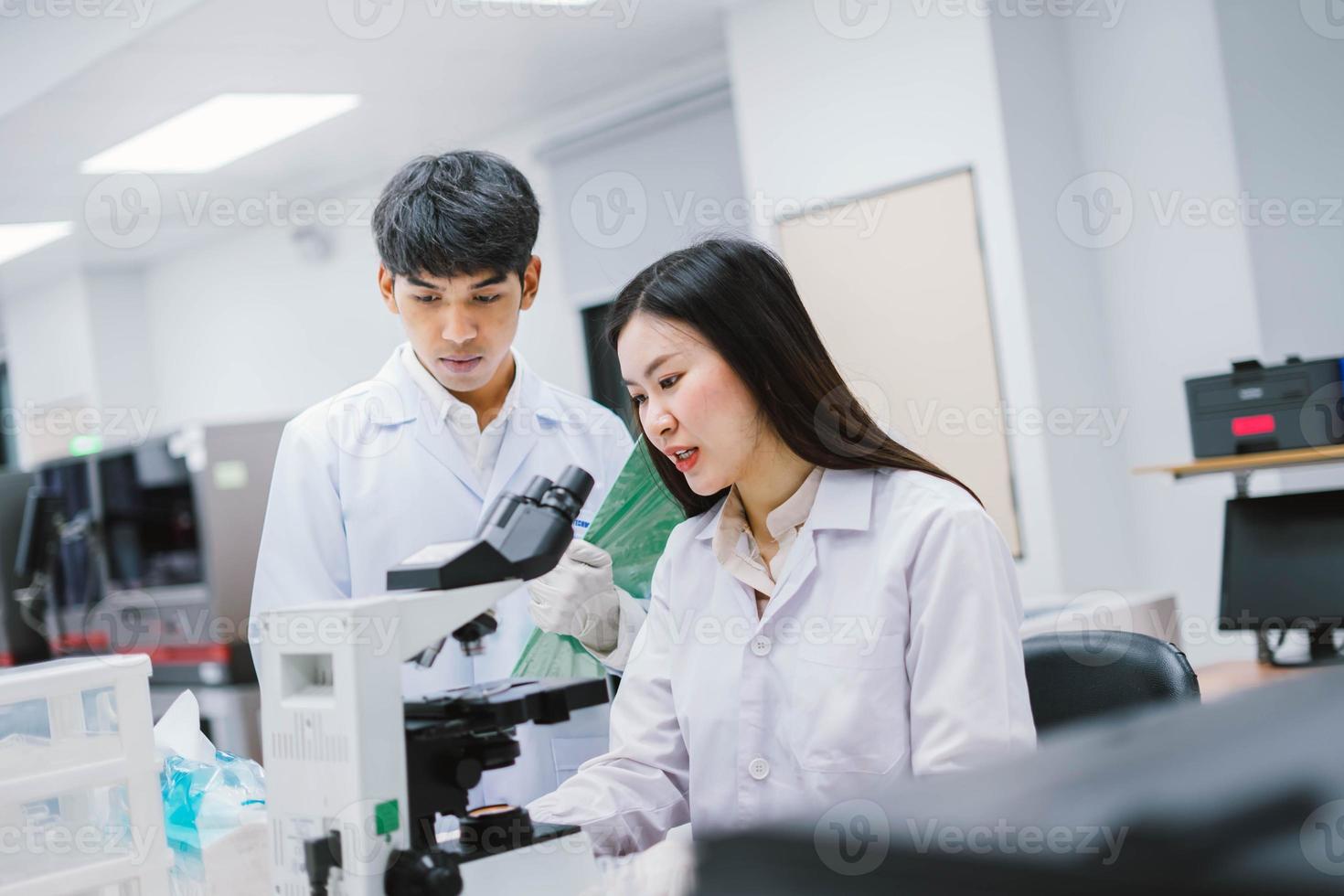 Two medical scientist working in Medical laboratory , young female scientist looking at microscope. select focus in young female scientist photo