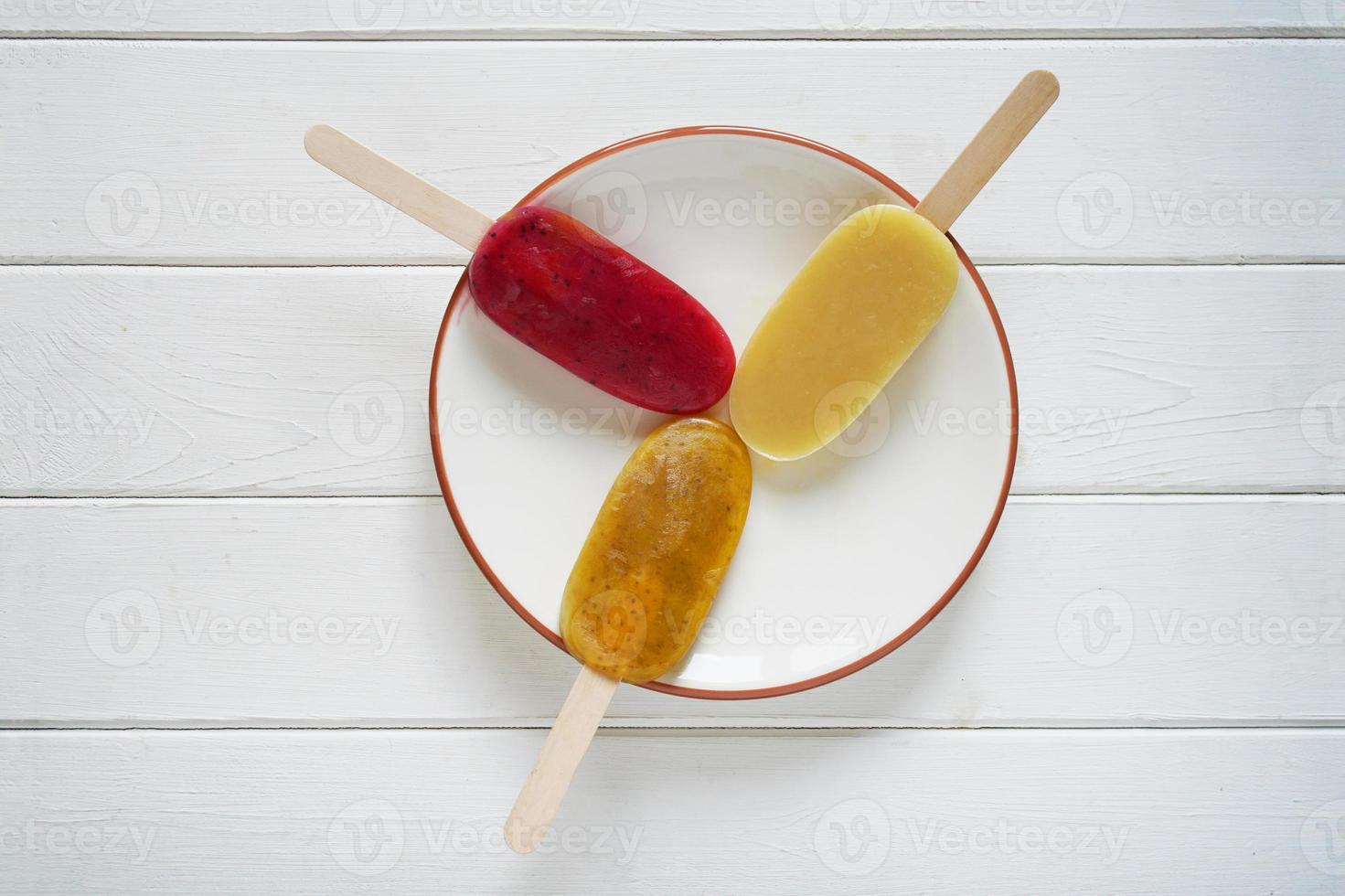 three different fruit smoothie popsicles or ice pops on a plate photo