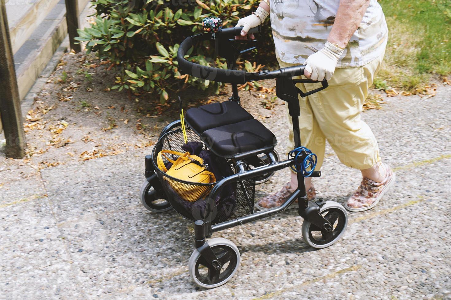 elderly woman walking outside with rollator or wheeled walker photo