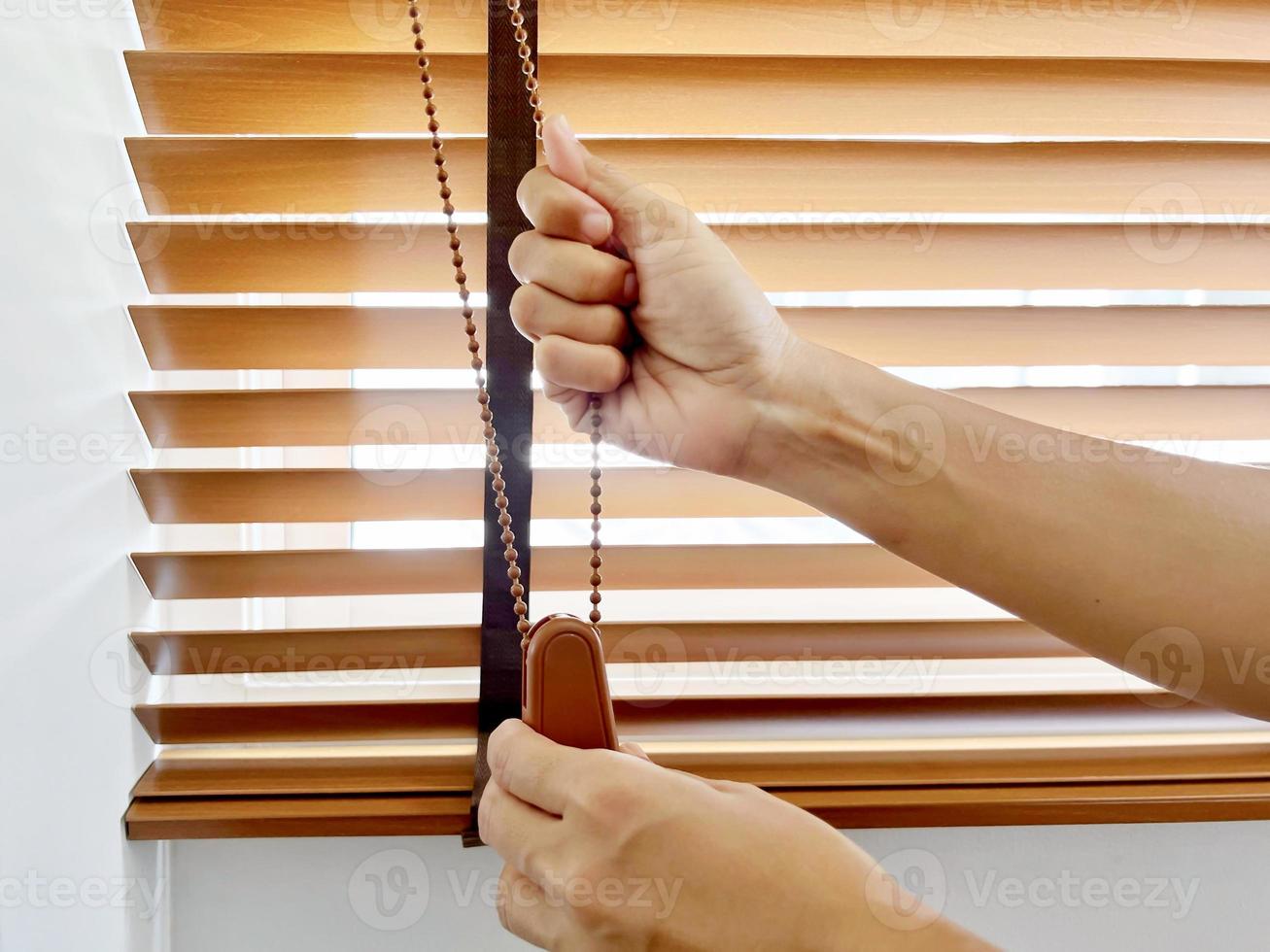 hands to close the window wooden blinds. photo