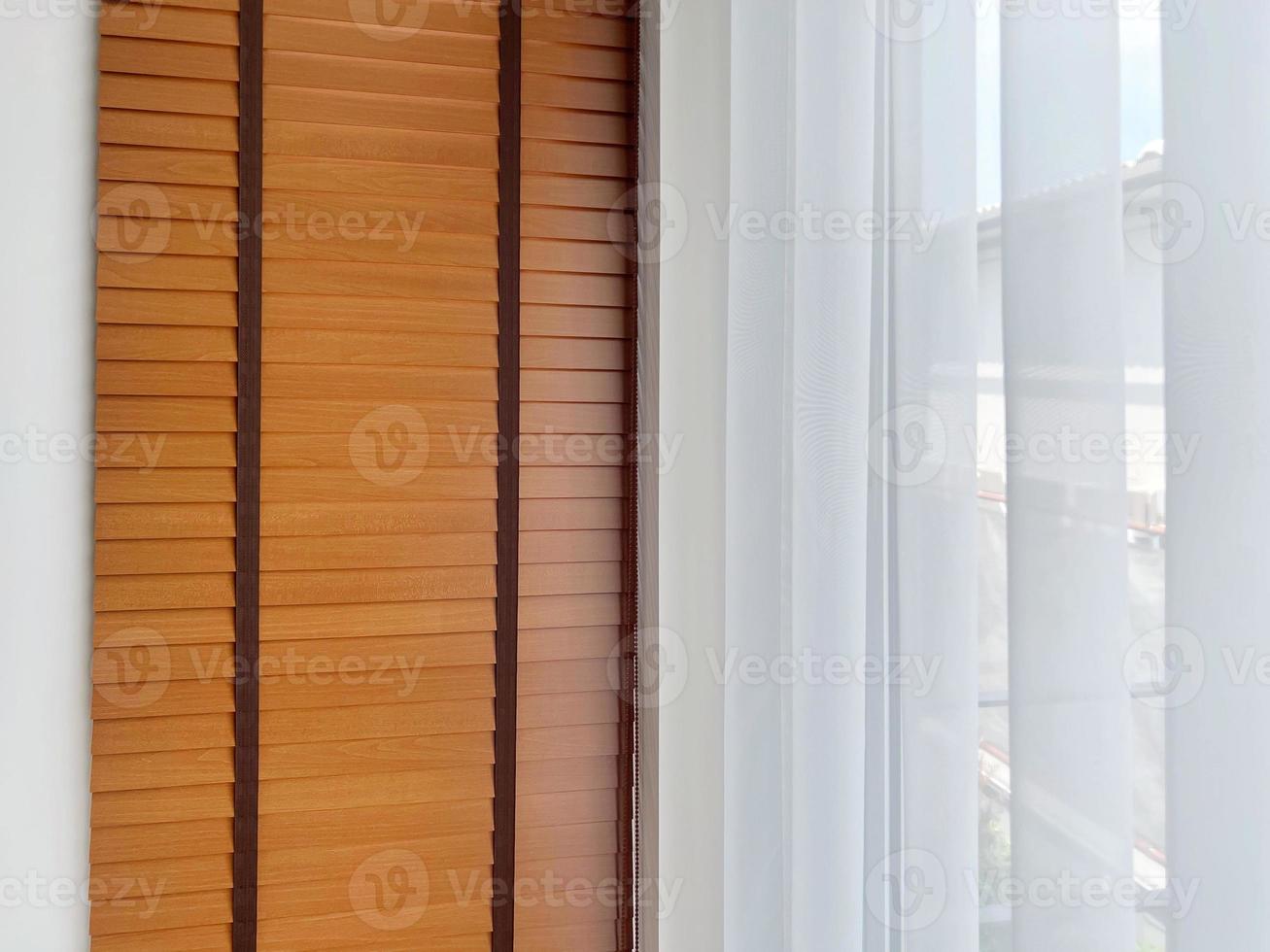 White sheer curtains with translucent fabric and wooden blinds hanging on window photo