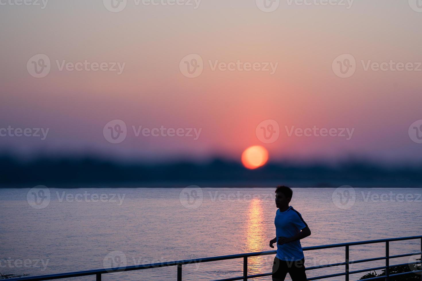 Man running on street with a view of river in the morning. photo