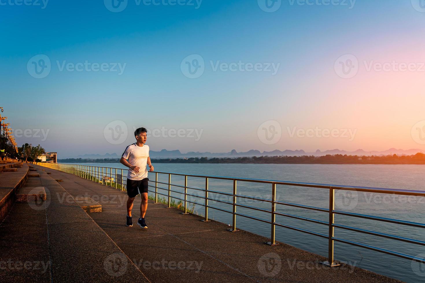 Man running on street with a view of river in the morning. photo