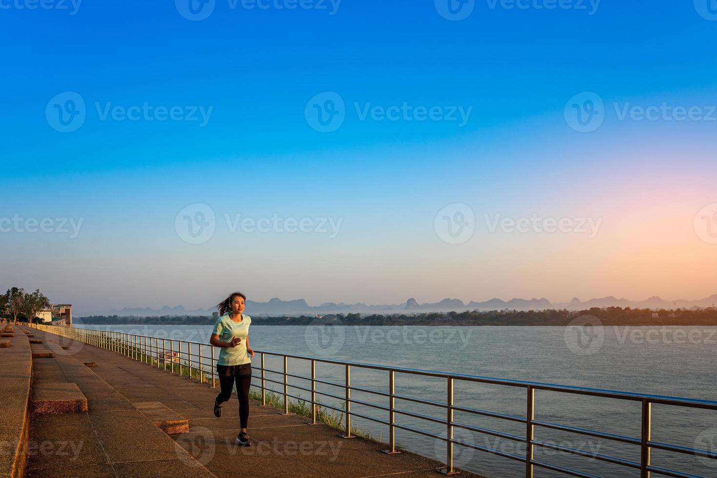 Woman running on street with a view of river in the morning. photo