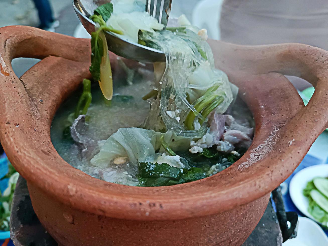 fideos de sopa, verduras, carne en un cuenco de cerámica sobre una mesa de madera tailandesa. foto