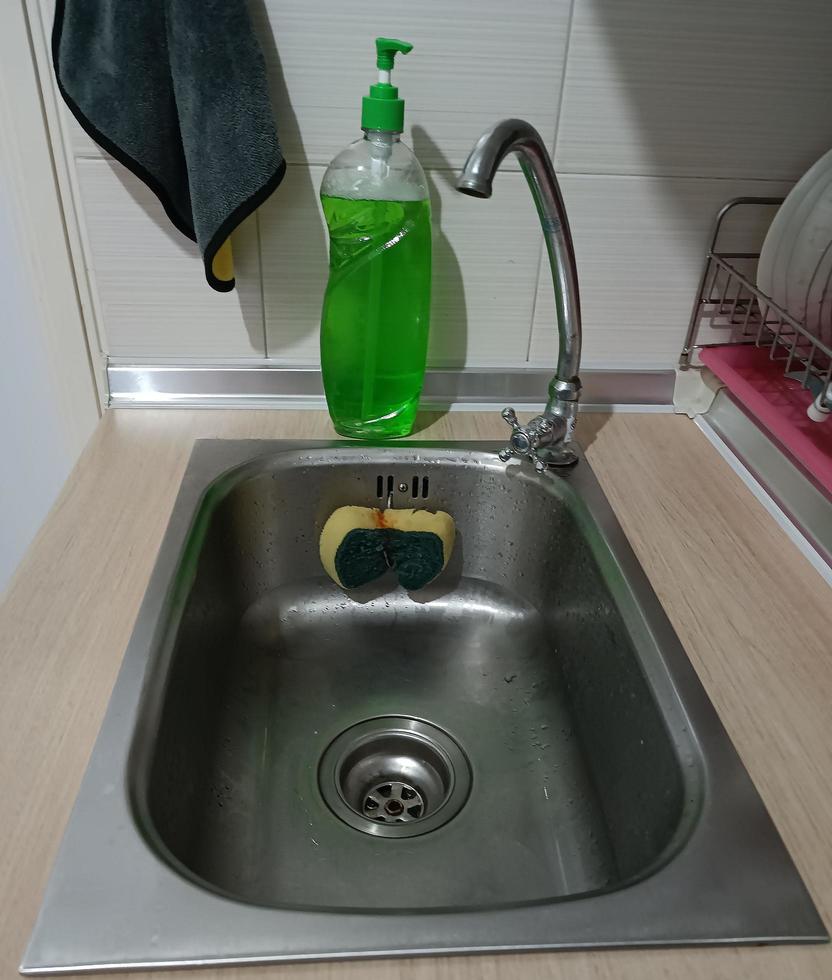 Sink with sponge and dishwashing liquid photo