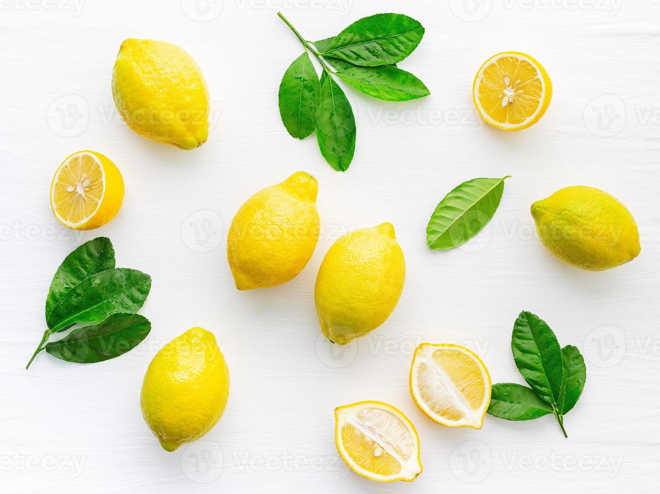 Fresh lemons and  lemons leaves on white wooden background. photo