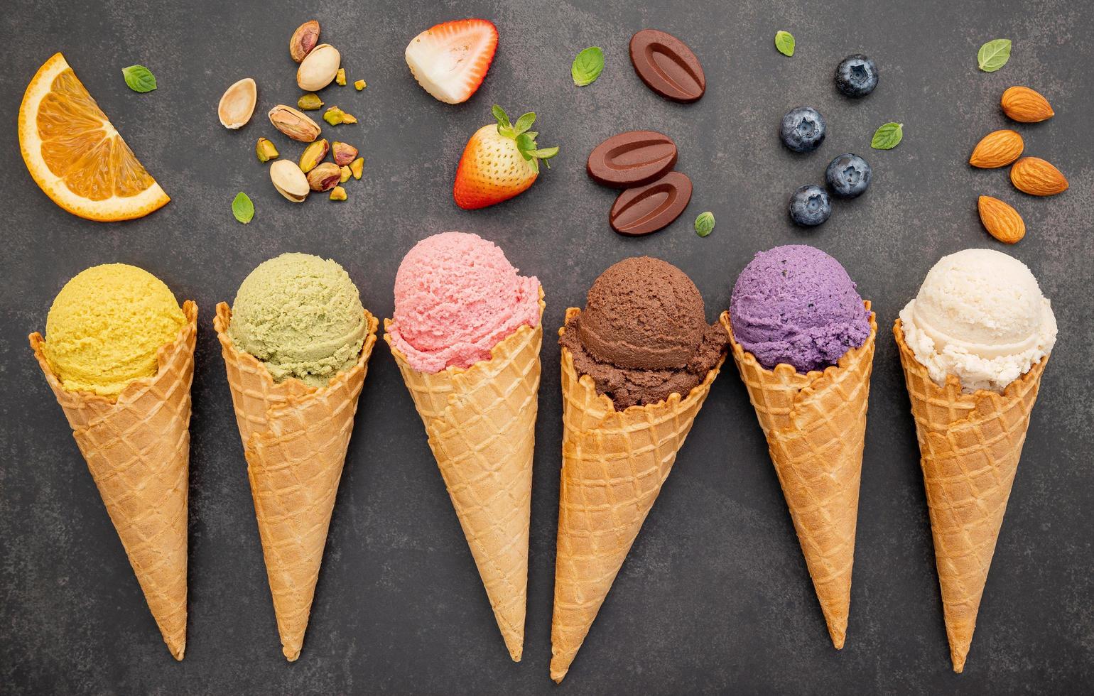 Various of ice cream flavor in cones blueberry ,pistachio ,almond ,orange and chocolate setup on dark stone background . Summer and Sweet menu concept. photo