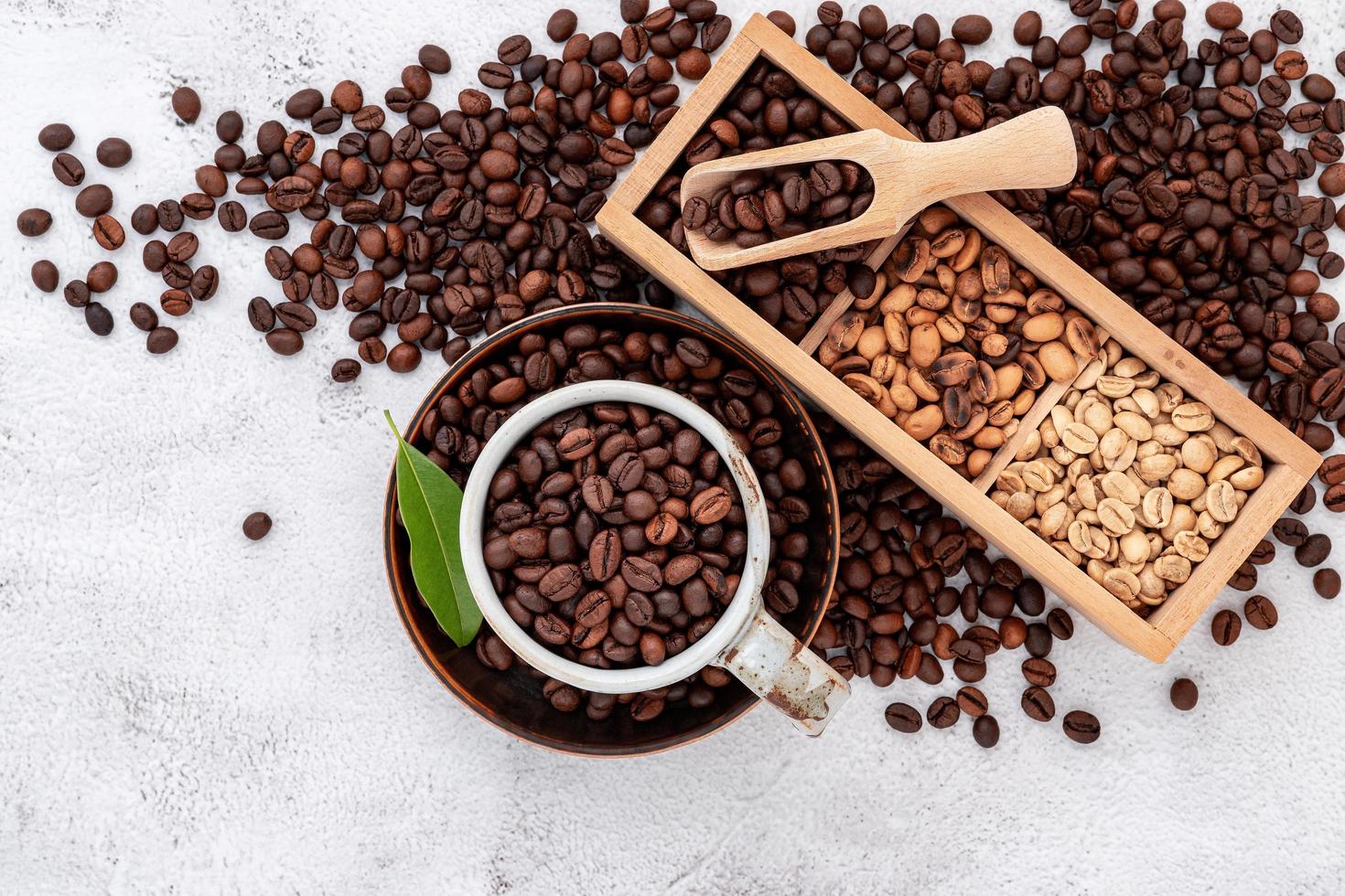 Roasted coffee beans with scoops setup on white concrete background. photo