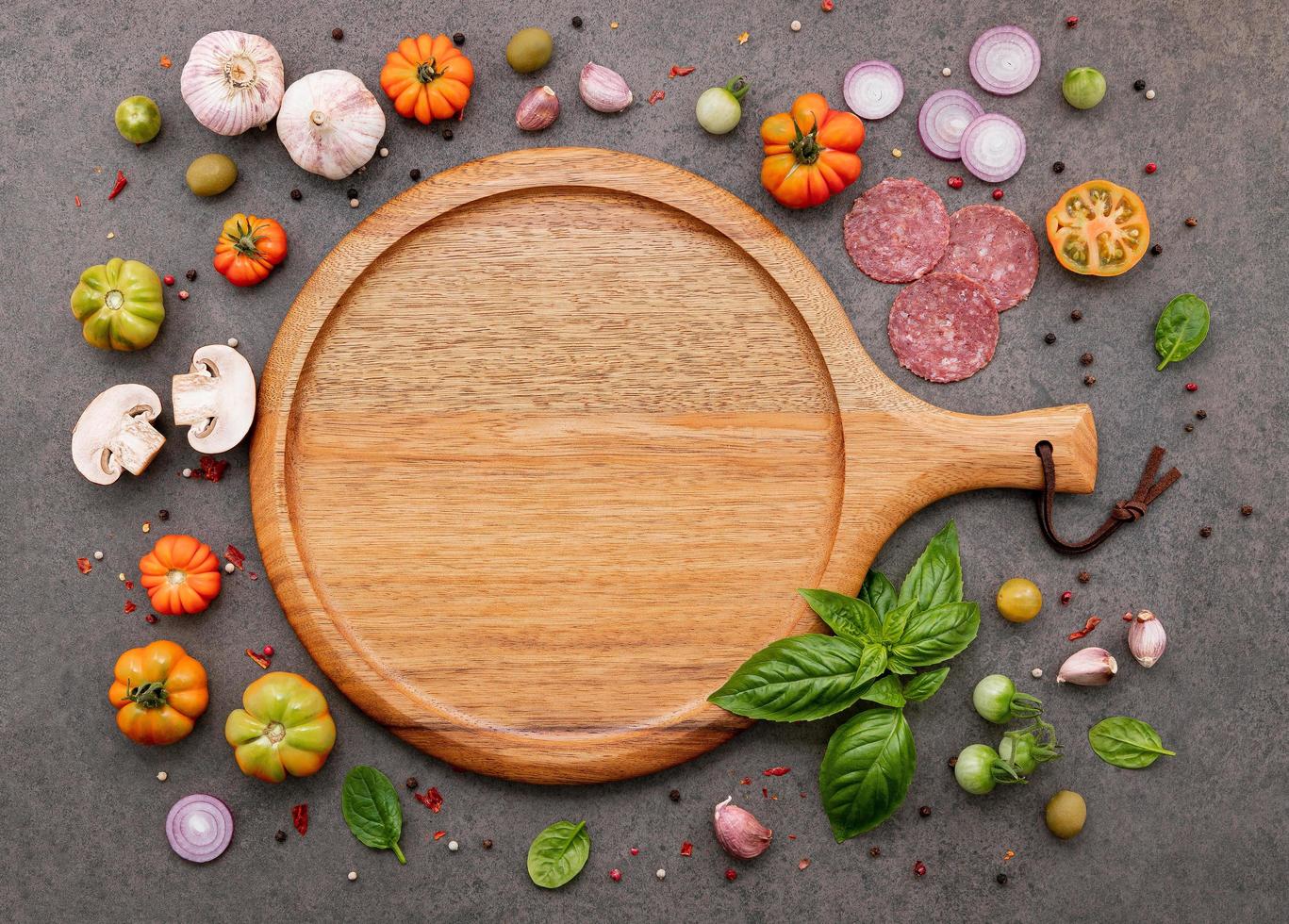 The ingredients for homemade pizza set up on dark stone background. photo