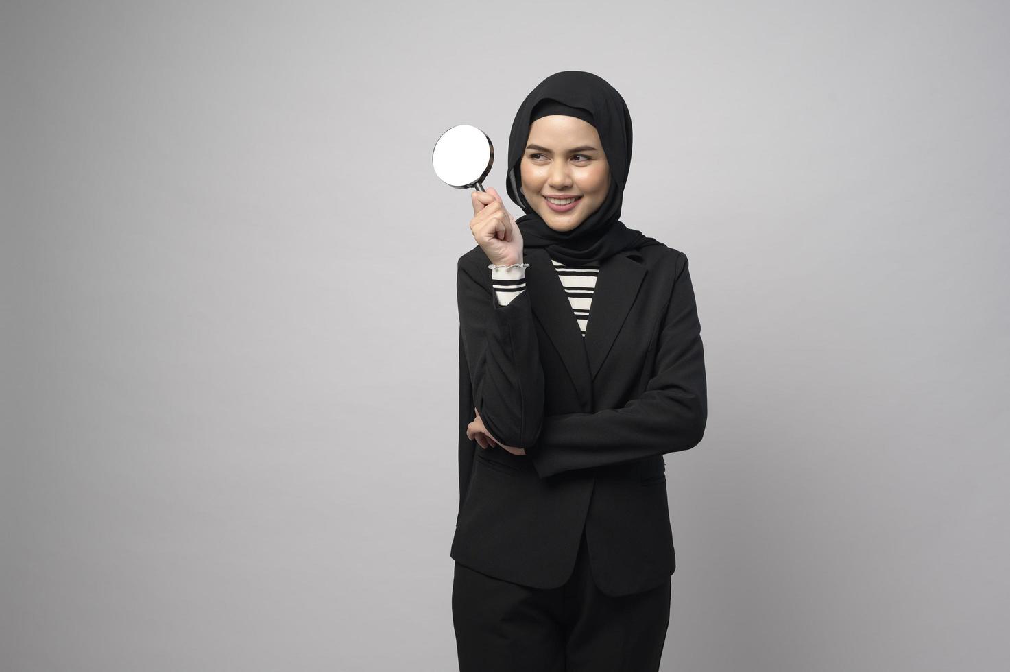 mujer de negocios musulmana sosteniendo lupa aislada sobre fondo blanco foto