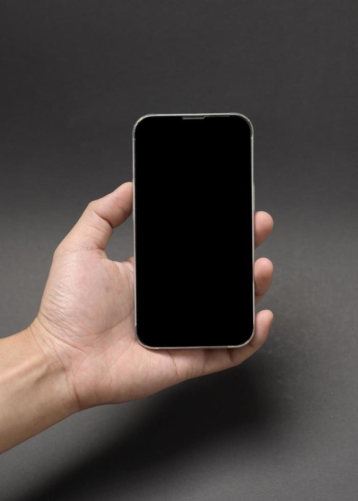 close up hand holding smart phone over black background studio photo