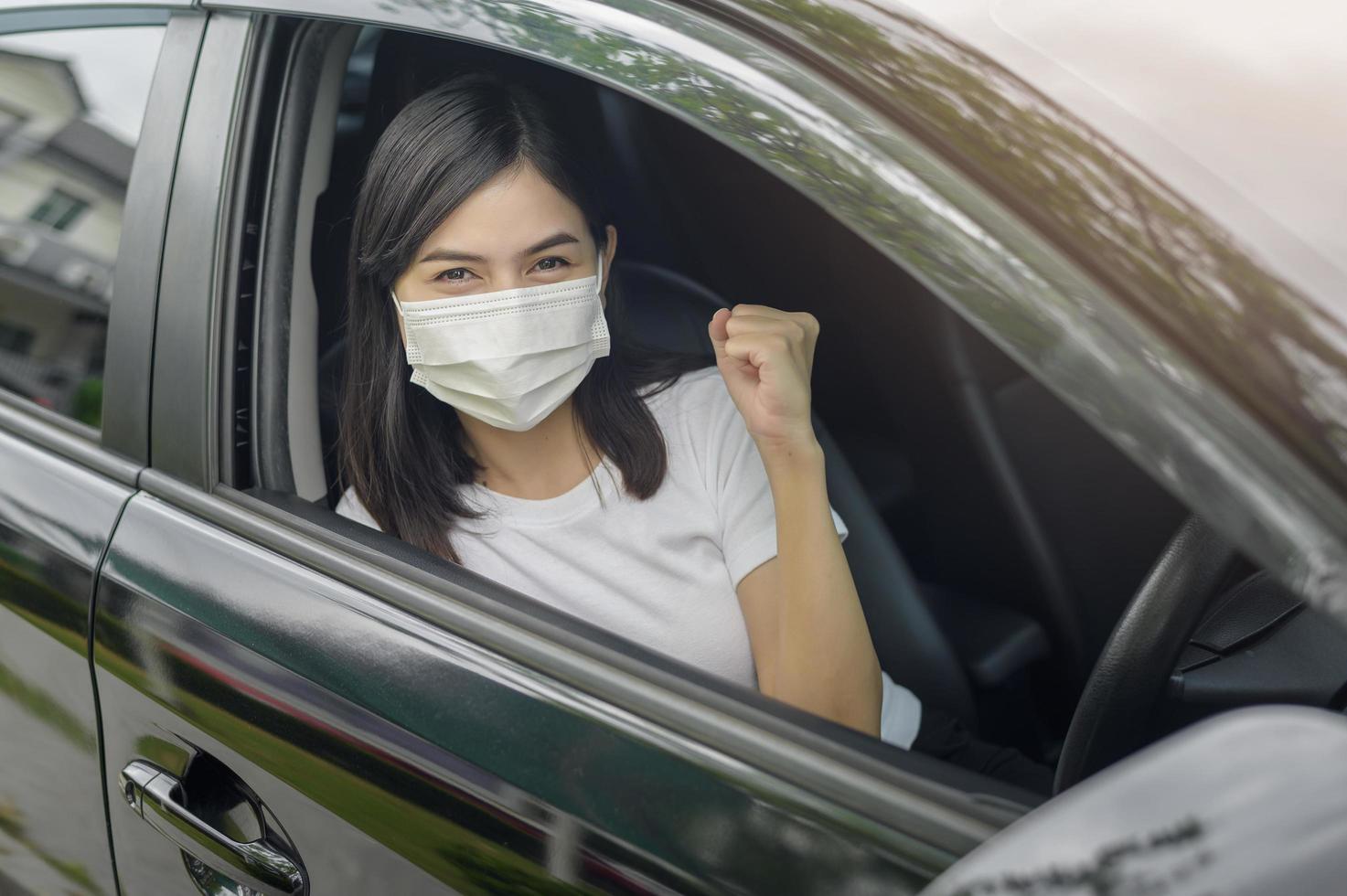Young beautiful woman wearing a protective mask driving a car photo