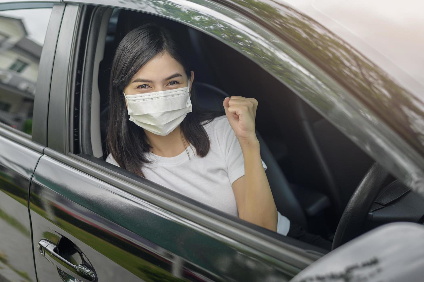 mujer hermosa joven con una máscara protectora conduciendo un automóvil foto