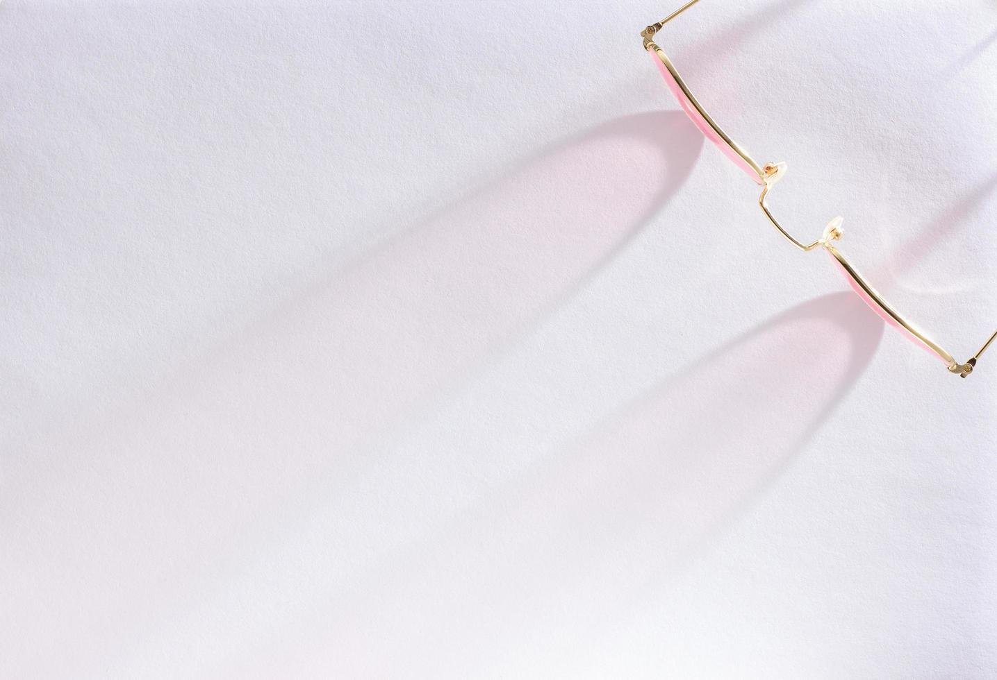 Top view of pink sunglasses on white background with sunlight shade with copy space. photo