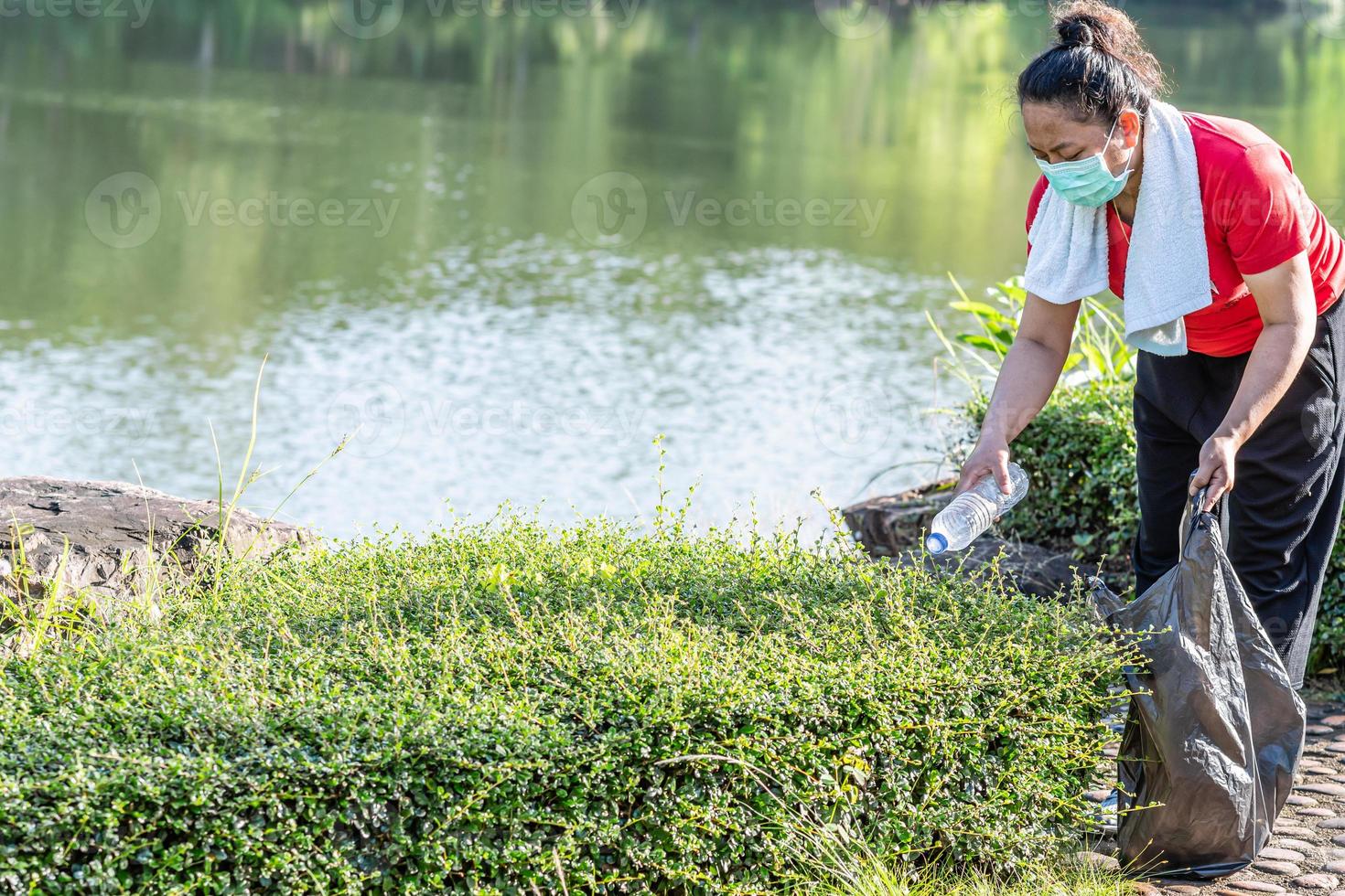 Woman cleans up by picking up plastic bottles at a natural water reservoir. Concept of protecting environment, saving world, recycling, reducing global warming, Earth Day. close up, blurred background photo