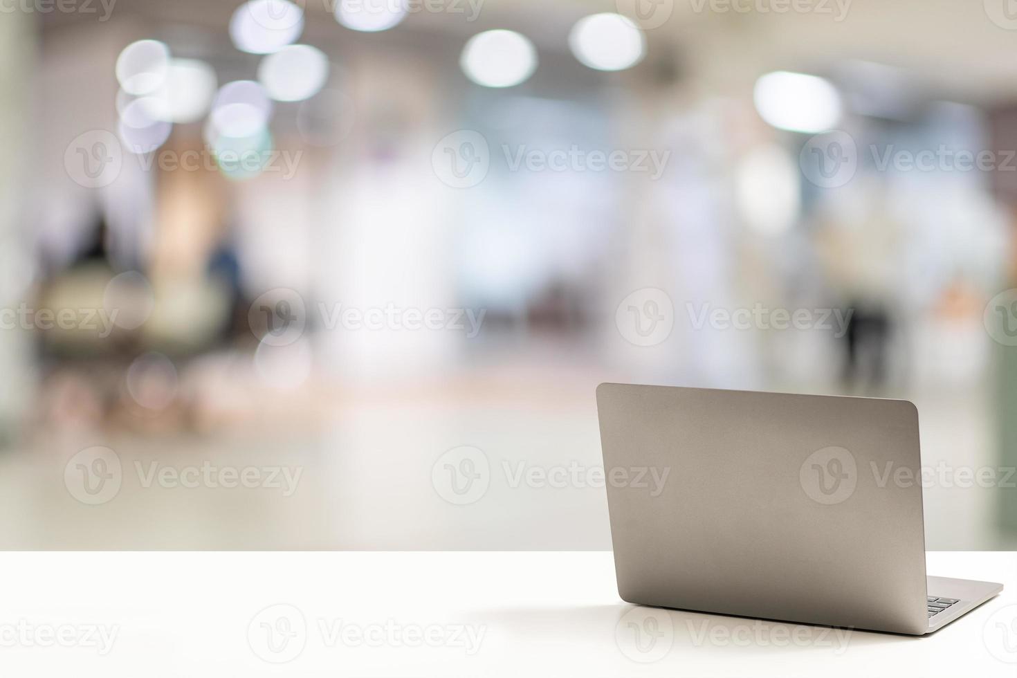 The back of the laptop is blank, placed on a white desk in an office, and nobody. Technology work concept, smartphone, notebook, internet, left side copy space, close up, Blurred background. photo