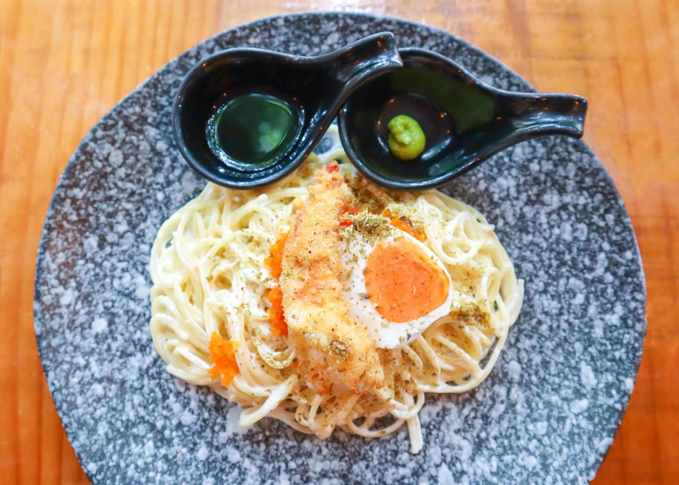 pasta cremosa de espaguetis con tempura de gambas y huevo de pato salado con salsa wasabi shoyu. foto