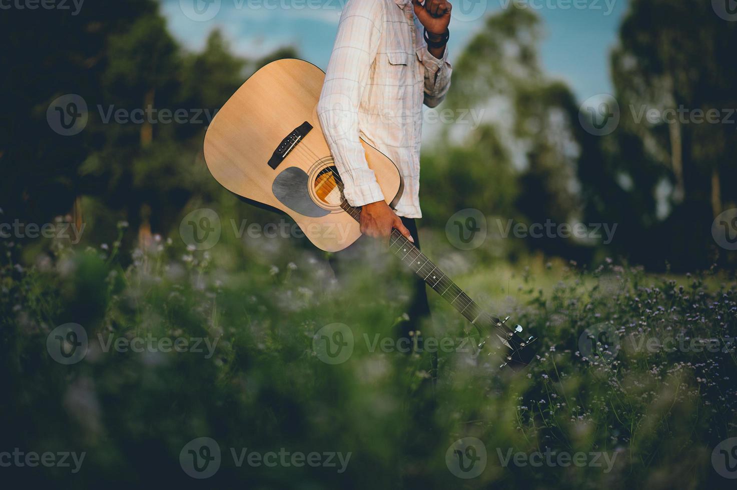 The man's hand plays the acoustic guitar, plays the guitar in the garden alone, happily and loves the music. photo