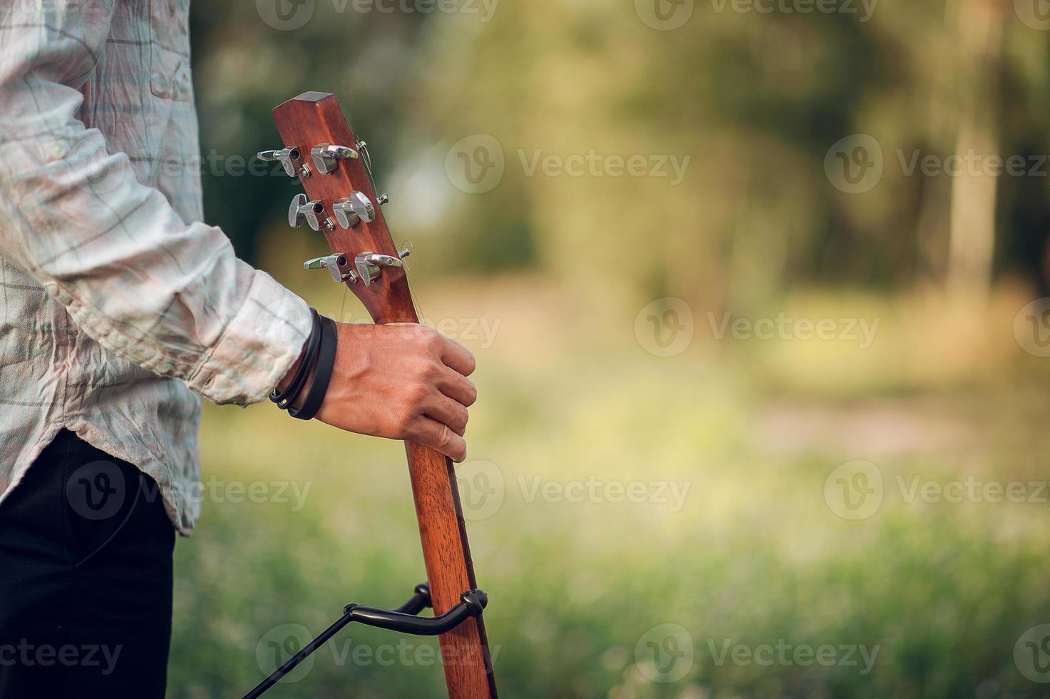 The man's hand plays the acoustic guitar, plays the guitar in the garden alone, happily and loves the music. photo