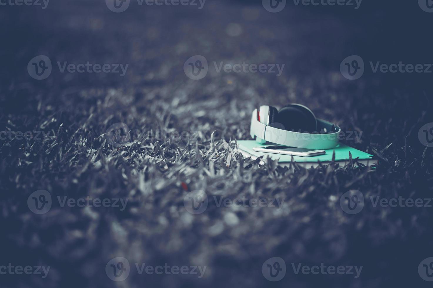 Hands and headphones are placed next to each other in green grass and moody music. Concepts of communication and listening. photo