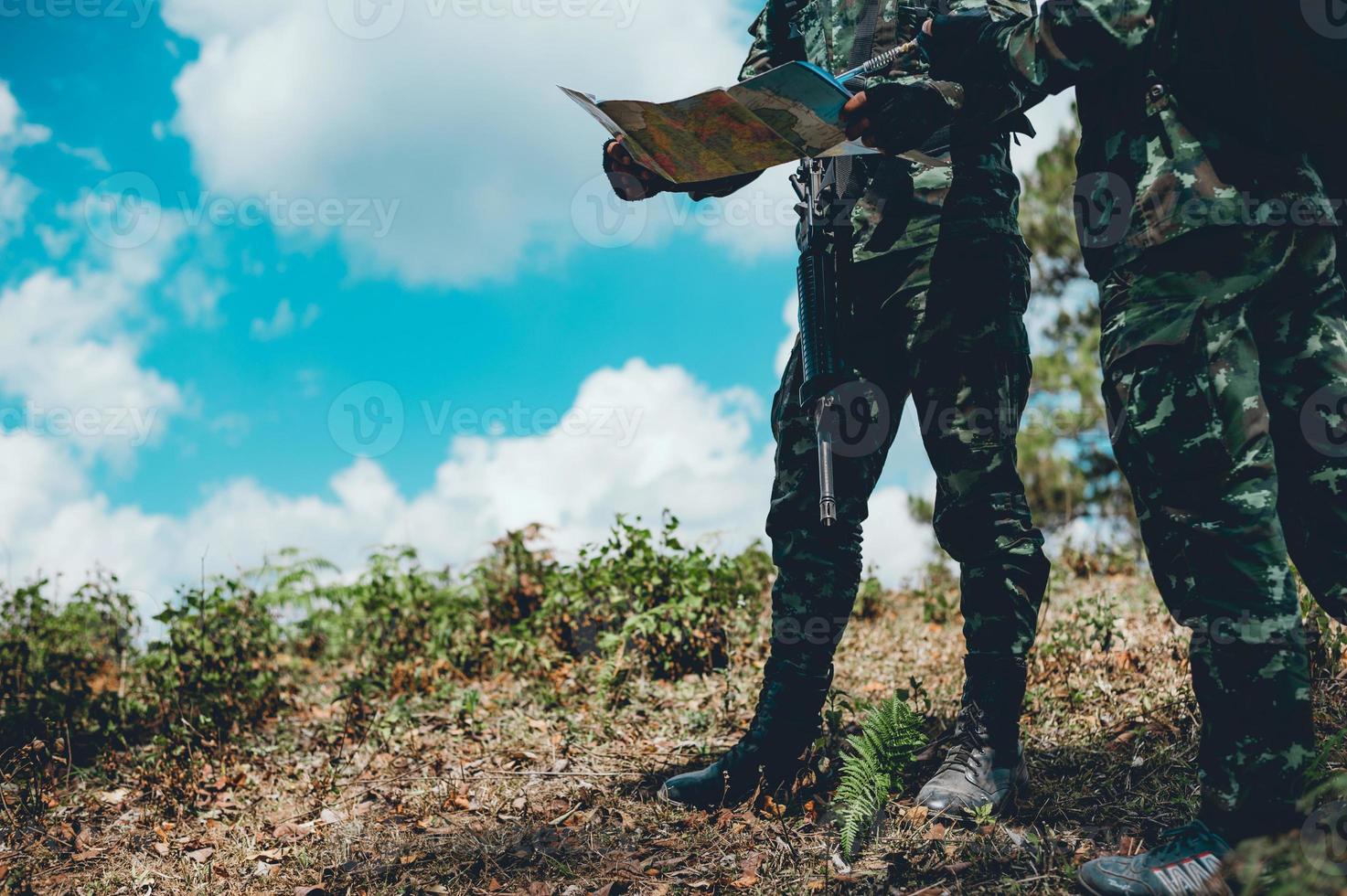 los soldados están usando la radio. y usar el mapa para la comunicación entre operaciones militares en el bosque fronterizo. guardián foto