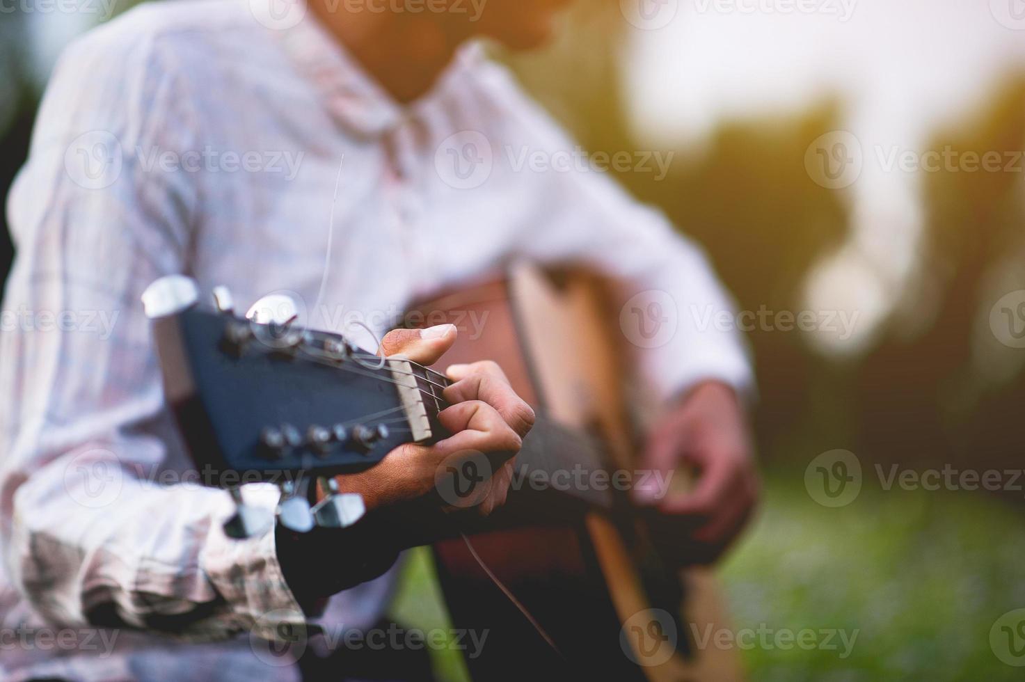 la mano del hombre toca la guitarra acústica, toca la guitarra en el jardín solo, alegremente y ama la música. foto