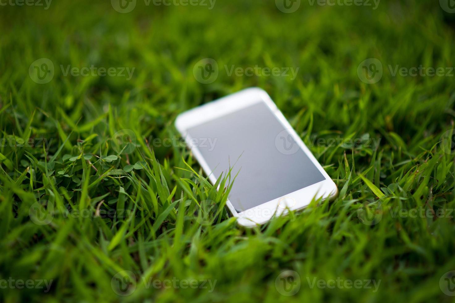 cellphone Placed in a light green grass. Every phone must have a home. Phone Concept photo