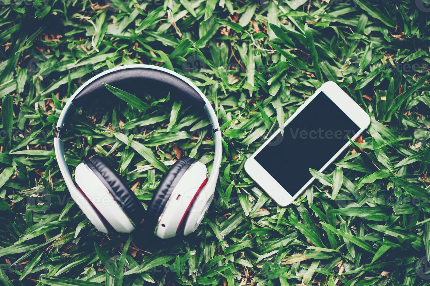 Hands and headphones are placed next to each other in green grass and moody music. Concepts of communication and listening. photo