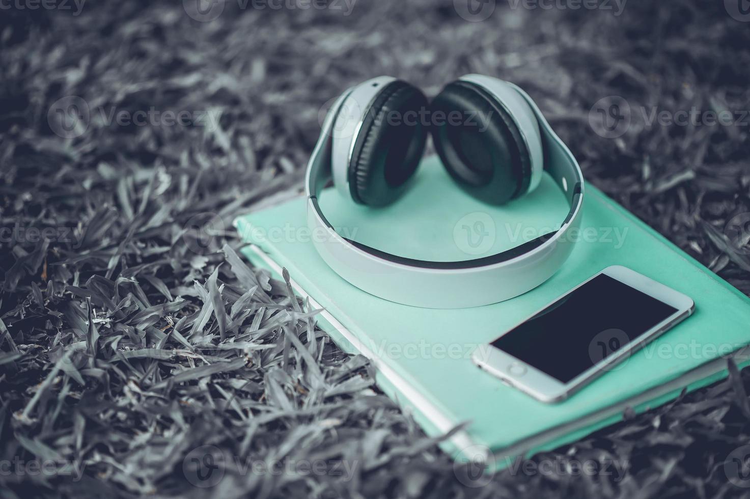 Hands and headphones are placed next to each other in green grass and moody music. Concepts of communication and listening. photo