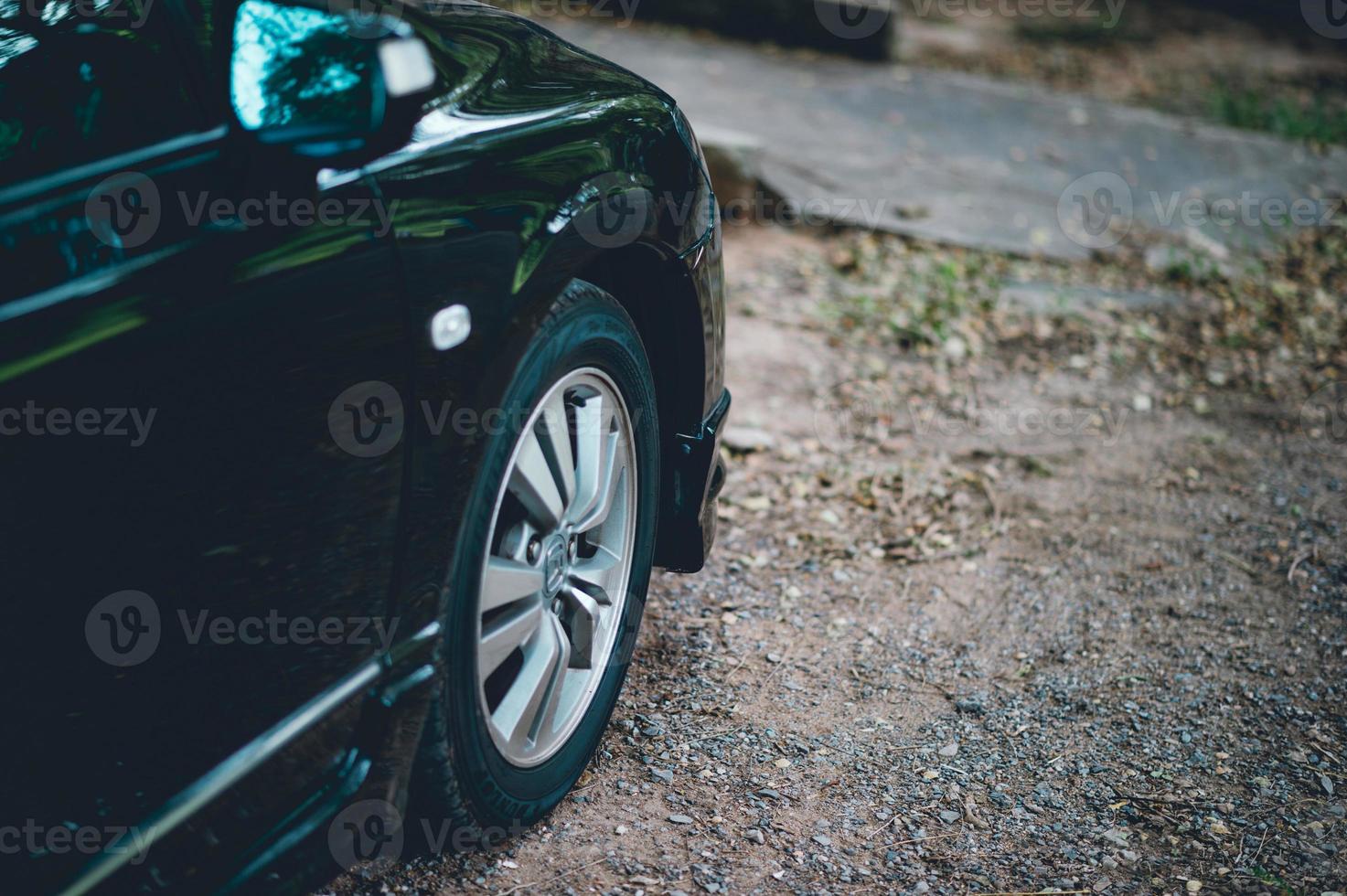 Cars and wheels, black front car parked in the ground along the way. And the side of the car. photo