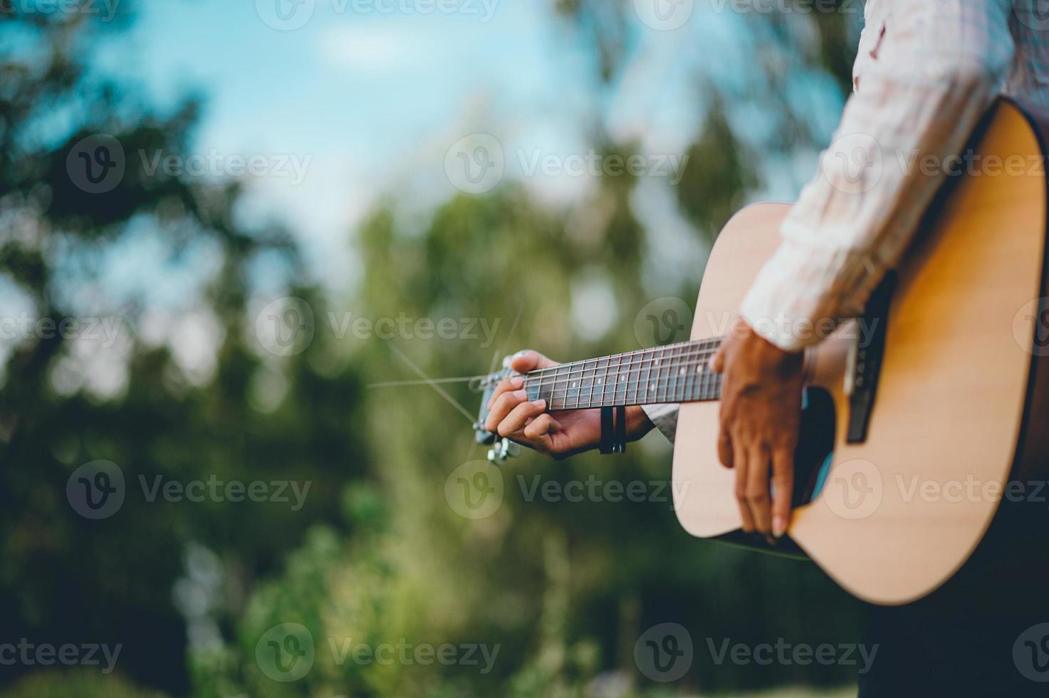 The man's hand plays the acoustic guitar, plays the guitar in the garden alone, happily and loves the music. photo
