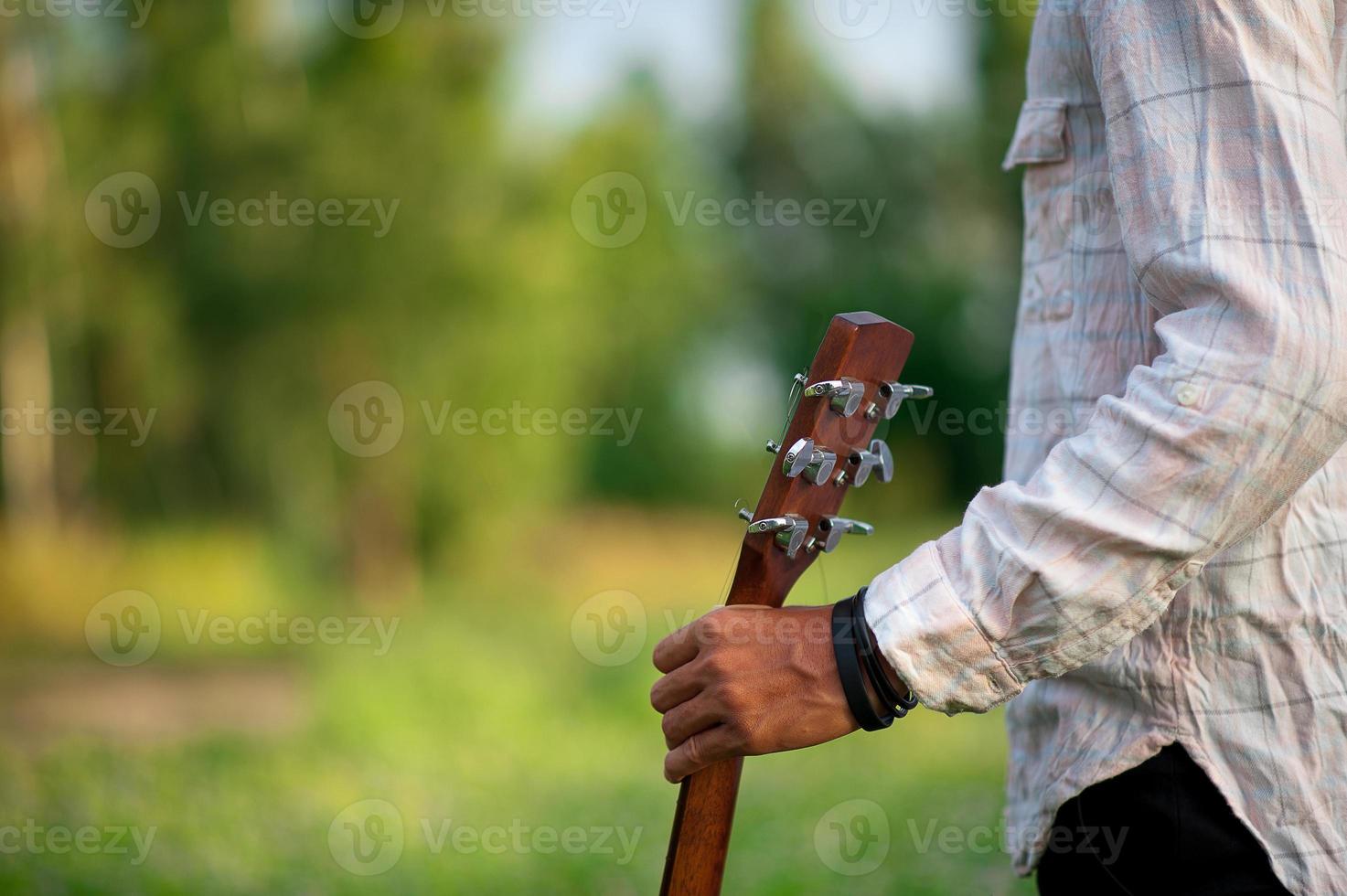 The man's hand plays the acoustic guitar, plays the guitar in the garden alone, happily and loves the music. photo