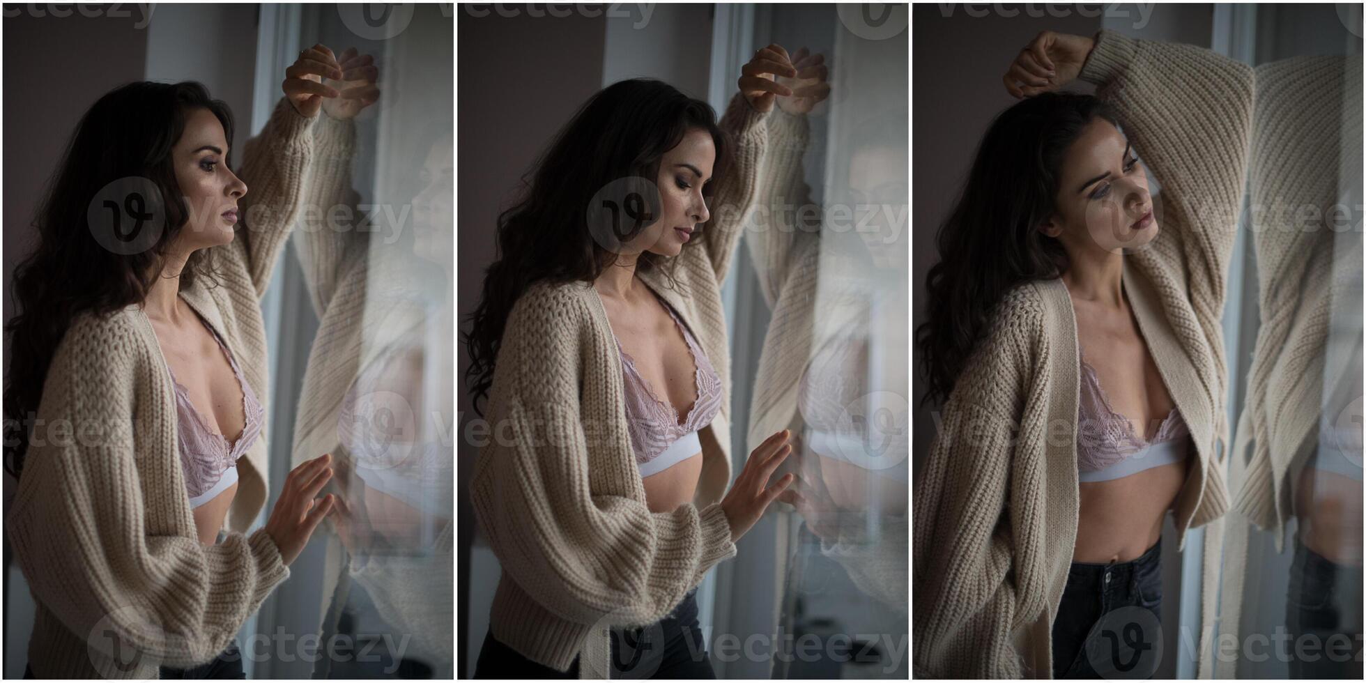 atractiva morena sexy en sujetador blanco y suéter marrón posando provocativamente, cerca de una ventana, toma de estudio. retrato de una mujer sensual con el pelo largo, en una clásica escena de boudoir, miró por la ventana foto