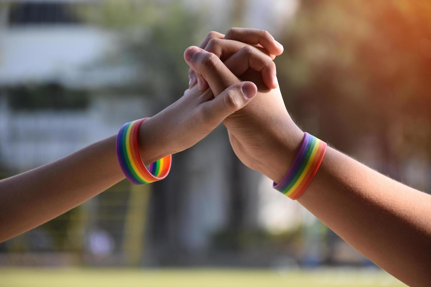 pulseras de goma arcoiris en las muñecas de una pareja de niños asiáticos con antecedentes borrosos, concepto para la celebración de la comunidad lgbt en el mes del orgullo o en junio en todo el mundo. foto