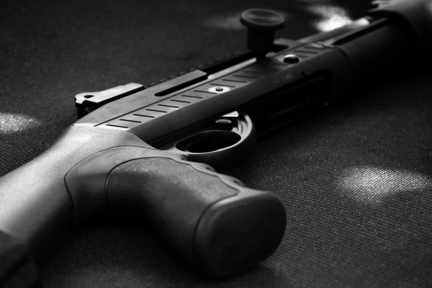 Closeup view of black shotgun which is on the black leather background, concept for shooting sport, security and bodyguard training, soft and selective focus. photo