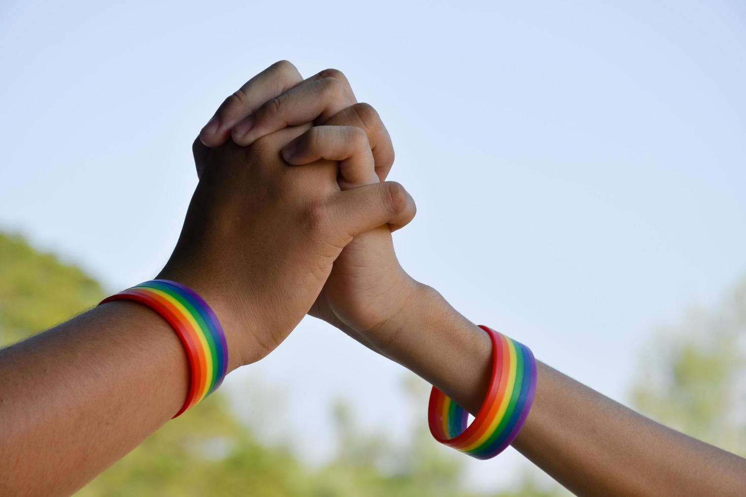 pulseras de goma arcoiris en las muñecas de una pareja de niños asiáticos con antecedentes borrosos, concepto para la celebración de la comunidad lgbt en el mes del orgullo o en junio en todo el mundo. foto