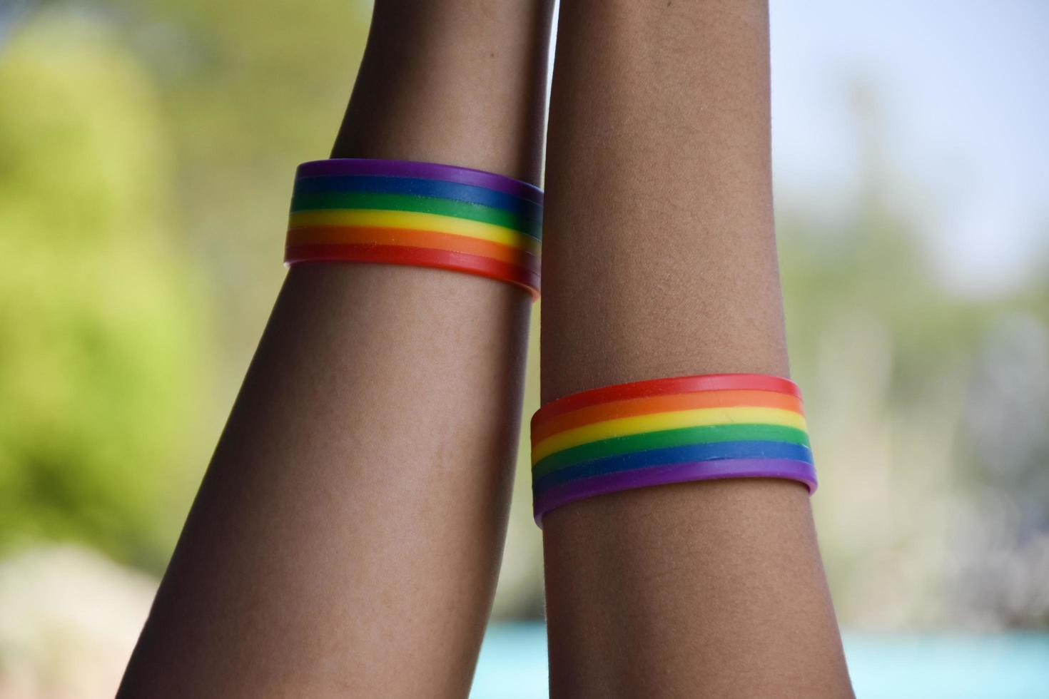 Rainbow rubber wristbands in wrists of asian boy couple with blurred background, concept for celebration of lgbt community in pride month or in June around the world. photo