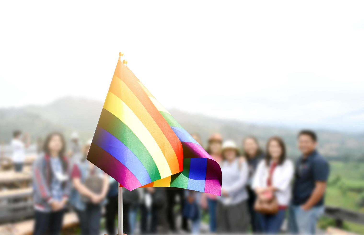 Pride rainbow lgbt gay flag holding in hand and being waved in the breeze against blue sky. photo