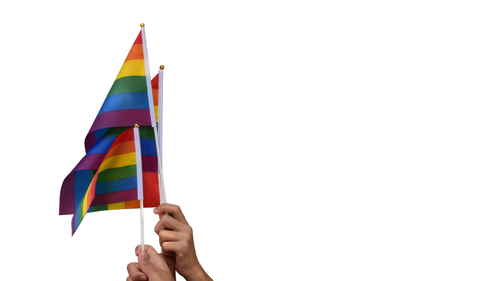 Pride rainbow lgbt gay flags holding in hand and being waved in the breeze against blue sky. photo